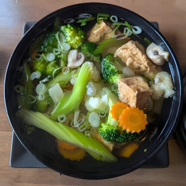 A bowl of Pho City's vegetarian pho with tofu, broccoli, cauliflower, mushrooms, and carrots.