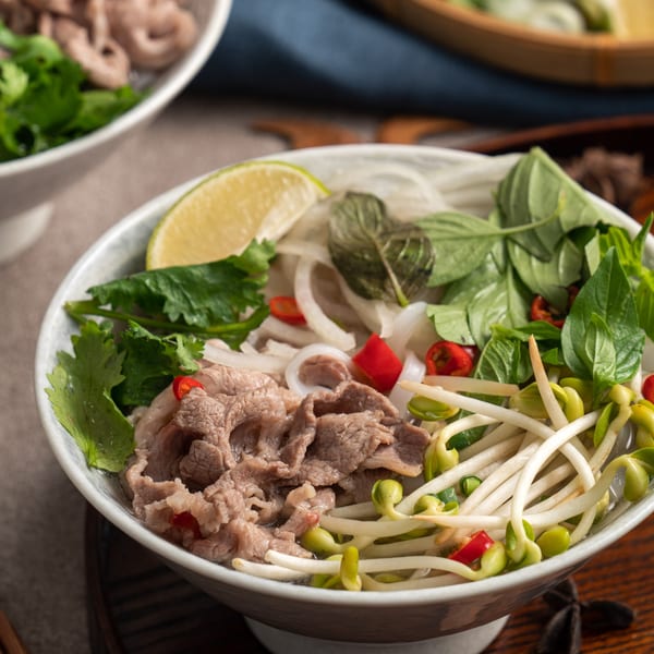 Close-up of Pho City's Vietnamese pho with beef, noodles, bean sprouts, herbs, and lime.